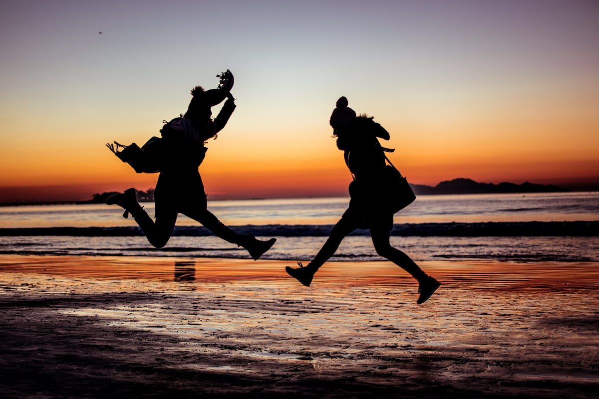 Silhouette of Persons Jumping in the Beach at Sunset